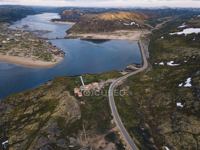 Rusia, Óblast de Murmansk, Teriberka, Vista aérea de la carretera alpina que se extiende más allá de la aldea de montaña - foto de stock