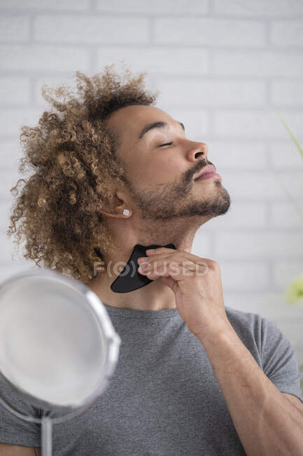 Молодий чоловік масажує шию з каменем гуа. — стокове фото