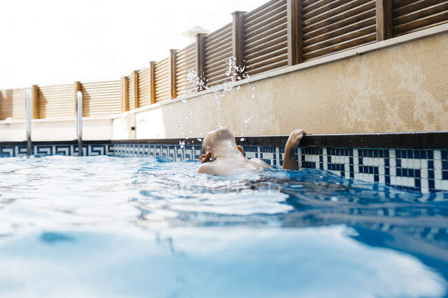 Ragazzo che gioca in piscina durante l'estate — Foto stock