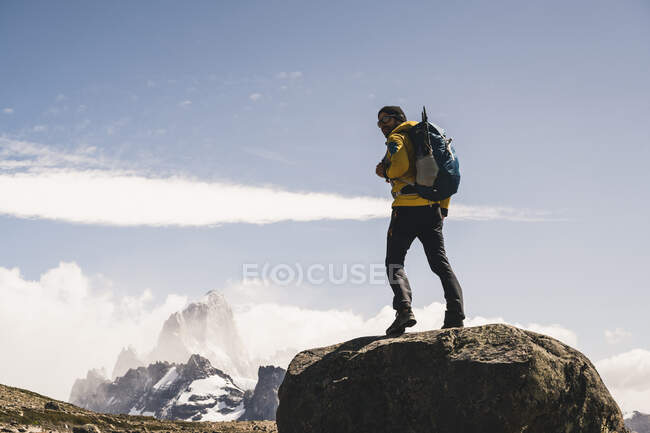 Чоловічий турист з рюкзаком, що стоїть на скелі проти неба в сонячний день, Патагонія, Аргентина. — стокове фото