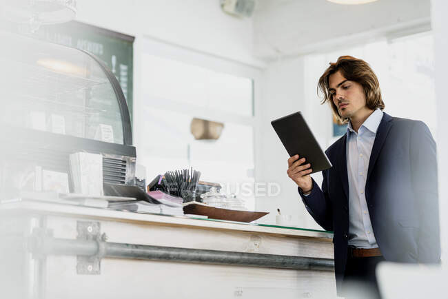 Чоловік - підприємець користується цифровою табличкою, стоячи в кав 