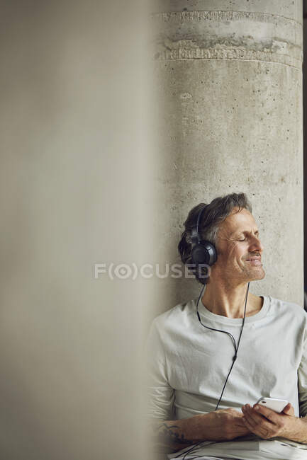 Senior man with headphones listening music in a loft flat — Stock Photo