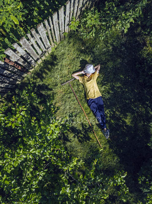 Veduta aerea della donna adulta media poggiata su terreni erbosi in giardino — Foto stock