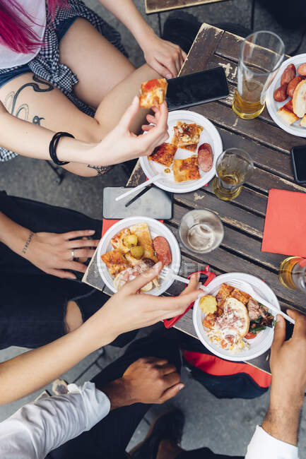 Freunde sitzen draußen am Tisch und essen Snacks — Stockfoto