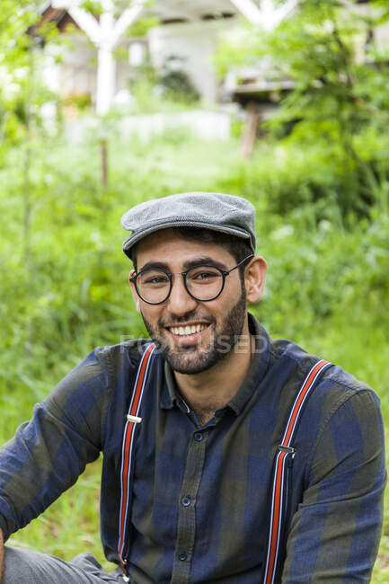 Retrato de um jovem sorridente usando óculos e boné — Fotografia de Stock