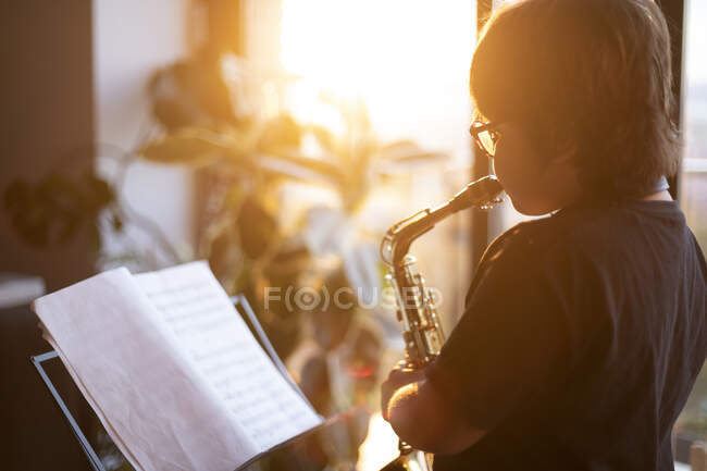 Ragazzo che si allena per suonare il sassofono a casa la sera — Foto stock