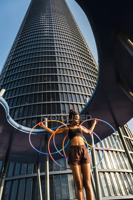 Femme sportive faisant de l'exercice avec des cerceaux en plastique à l'extérieur du bâtiment — Photo de stock
