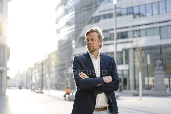 Бізнесмен стоїть у місті і дивиться убік. — стокове фото