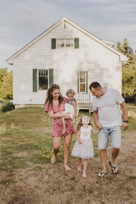 Glückliche Eltern mit zwei Töchtern vor ihrem Haus — Stockfoto