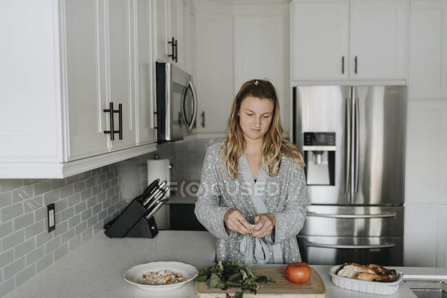 Mitte erwachsene Frau bereitet Salat zu Hause auf Küchentheke zu — Stockfoto