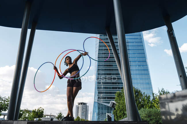 Спортивна жінка, яка врівноважує пластикові обручі в сучасному місті. — стокове фото