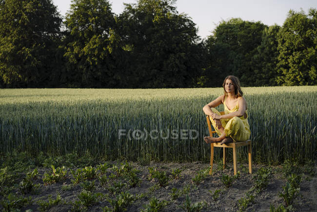 Young woman sitting on a chair in the countryside — Stock Photo