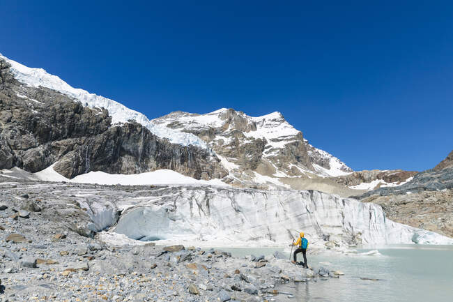 Älterer Mann wandert beim Erkunden des schneebedeckten Berges vor strahlend blauem Himmel — Stockfoto