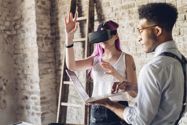 Two creative business people with VR goggles and laptop in loft office — Stock Photo