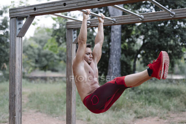 Homem levantando perna pendurado na selva ginásio — Fotografia de Stock