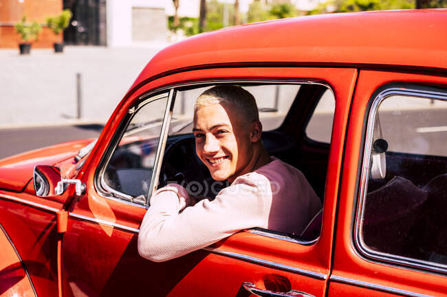 Retrato de adolescente feliz sentado no carro do vintage olhando pela janela — Fotografia de Stock