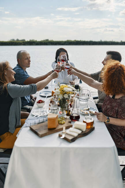 Amis dîner dans un lac cliquetis verres à vin — Photo de stock