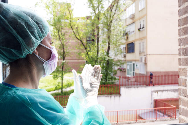 Медсестра плескає в долоні у вікно лікарні. — стокове фото