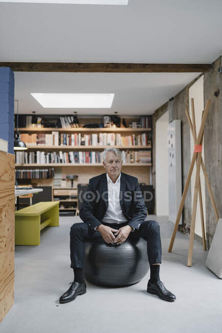 Senior businessman sitting on fitness ball, thinking — Stock Photo