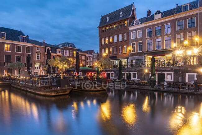 Netherlands, South Holland, Leiden, Cafes at edge of Nieuwe Rjin canal at dusk — Stock Photo
