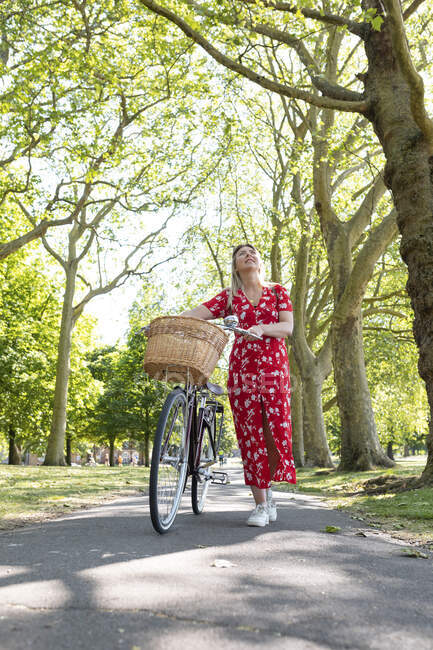 Mulher atenciosa andando com bicicleta no caminho do parque — Fotografia de Stock
