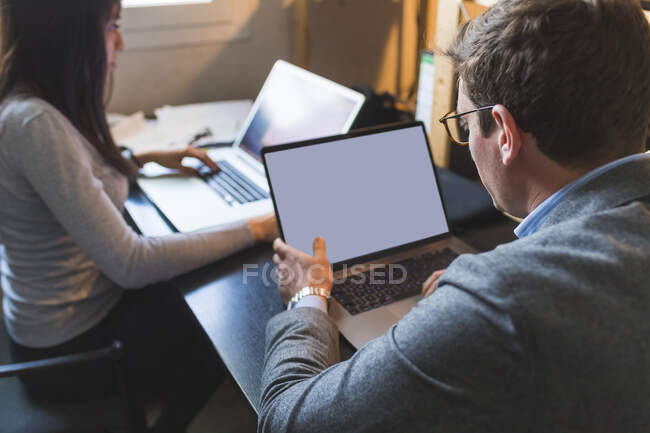 Uomo e donna d'affari che utilizzano computer portatili alla scrivania in ufficio — Foto stock