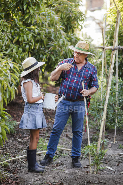 Uomo anziano che parla con nipote in giardino — Foto stock