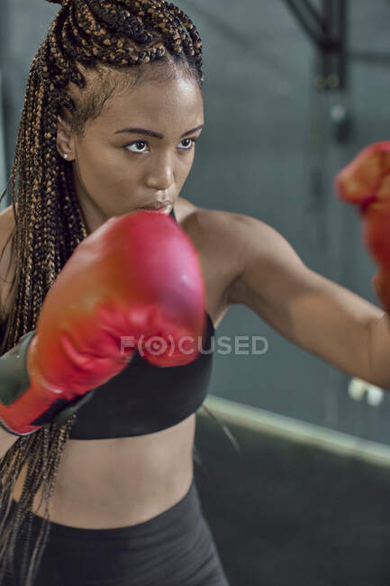 Gros plan d'une athlète portant des gants rouges pratiquant la boxe dans un gymnase — Photo de stock