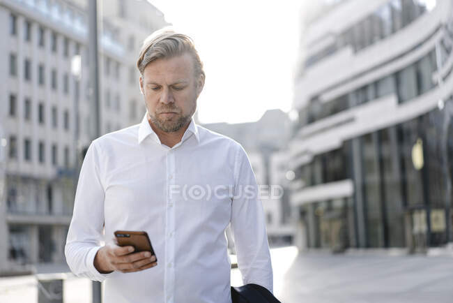 Homme d'affaires utilisant un smartphone dans la ville — Photo de stock
