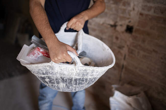 Trabalhador da construção transportando cesta com ferramentas no canteiro de obras — Fotografia de Stock