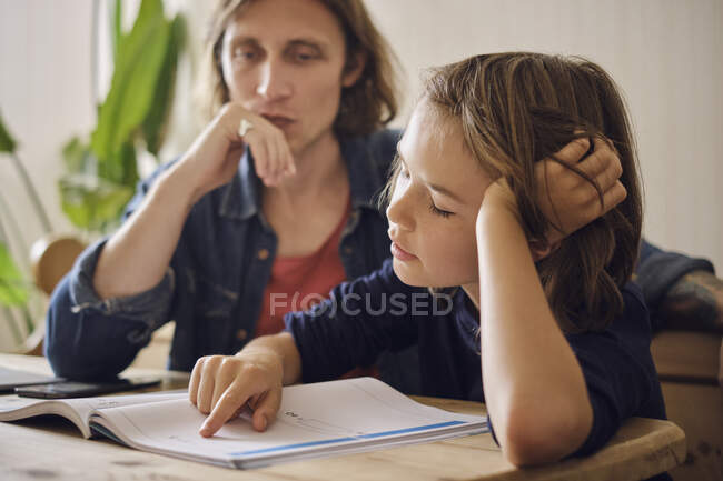 Padre che aiuta il figlio a fare i compiti a casa — Foto stock
