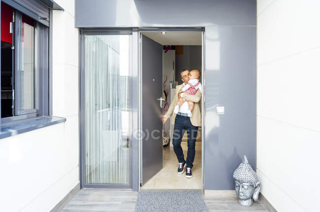 Батько тримає свого малюка і йде з дому. — стокове фото
