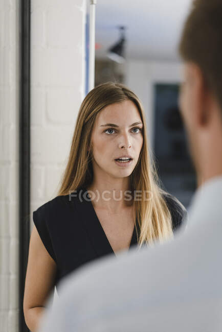 Joven mujer de negocios discutiendo con su colega en la oficina en una reunión - foto de stock
