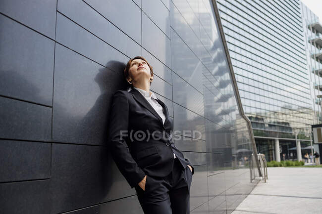 Thoughtful businesswoman standing by modern building in city — Stock Photo