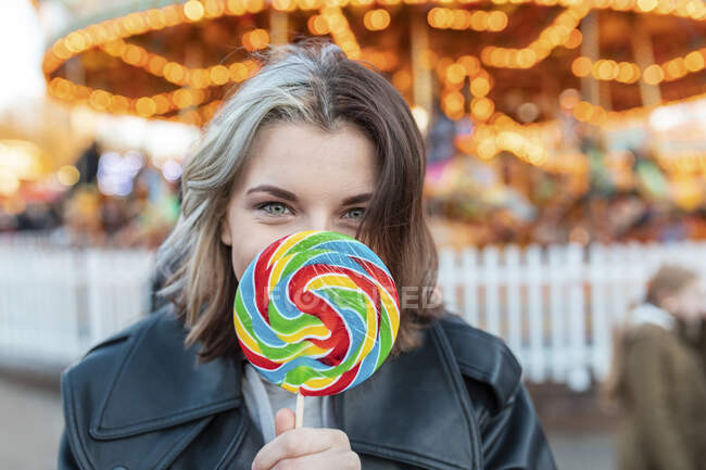 Close-up of young woman holding colorful lollipop at amusement park — Stock Photo