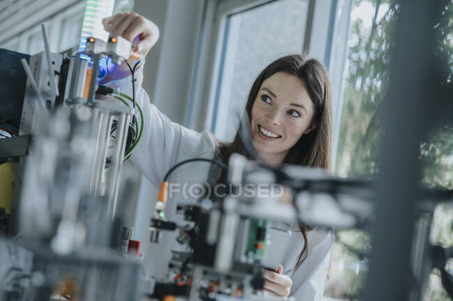 Усмішка молода жінка винаходить машини в лабораторії. — стокове фото