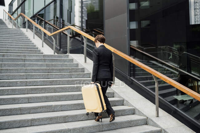 Businesswoman with suitcase walking on steps in city — Foto stock