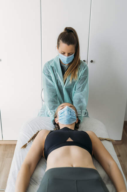 Doctor wearing face mask examining sportswoman — Stock Photo