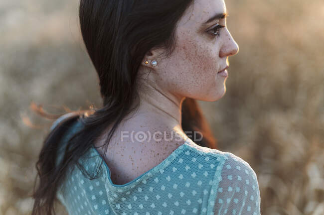 Nahaufnahme einer jungen Frau mit Sommersprossen im Gesicht, die in einem Bauernhof wegschaut — Stockfoto