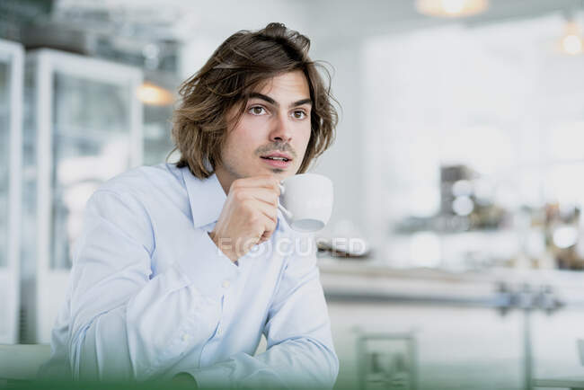 Pensativo profesional masculino beber café mientras está sentado en la cafetería - foto de stock