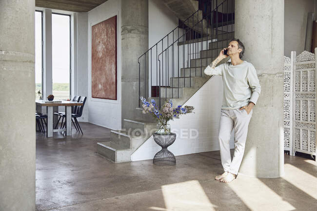 Senior man on the phone in a loft flat — Stock Photo