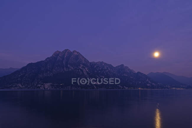 Italia, Lombardia, Riva di Solto, Lago d'Iseo e Corna Trentapassi di notte con luna piena — Foto stock