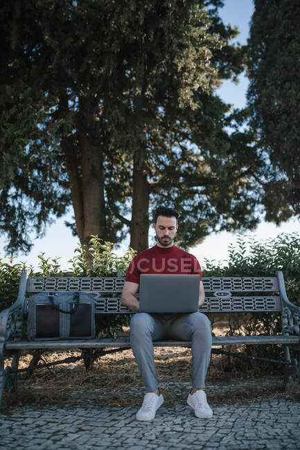 Geschäftsmann sitzt mit Laptop auf Bank im Park — Stockfoto