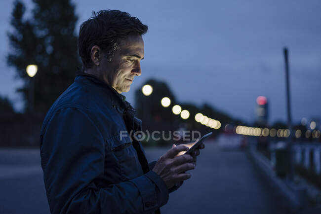 Mature man using tablet on a promenade at dusk — Stock Photo