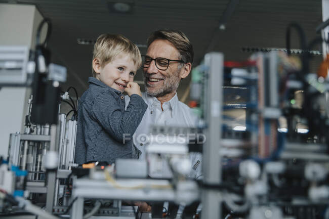 Scienziato sorridente che mostra macchinari al figlio in laboratorio in fabbrica — Foto stock