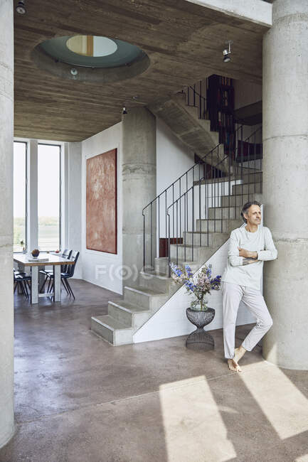 Senior man leaning against a column in a loft flat — Stock Photo