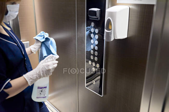 Camareira vestindo máscara de limpeza de botões de elevador no hotel — Fotografia de Stock