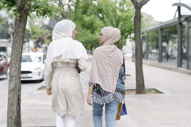 Мусульманские сестры разговаривают во время прогулки по городу — стоковое фото