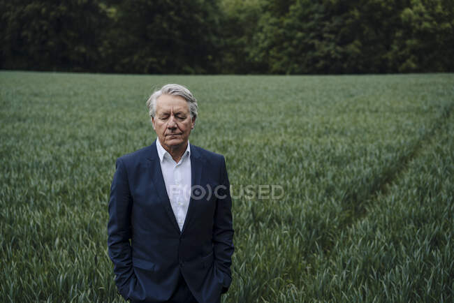 Портрет старшего бизнесмена с закрытыми глазами на поле в сельской местности — стоковое фото