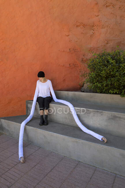 Donna con mani lunghe artificiali seduta su gradini di cemento dalle piante — Foto stock